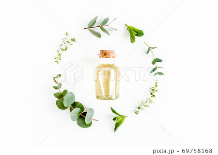 Essential oil and round wreath frame made of mix of herbs, green branches, leaves mint, eucalyptus, thyme and plants collection on white background. Essential oil and round wreath frame made of mix of herbs, green branches, leaves mint, eucalyptus, thyme and plants collection on white background. 69758168