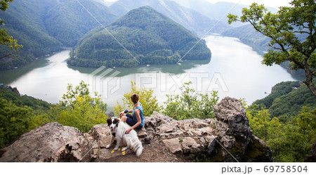 woman and dog on mountain top above lake 69758504