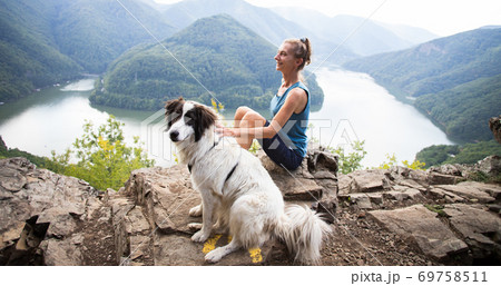 woman and dog on mountain top above lake woman and dog on mountain top above lake 69758511