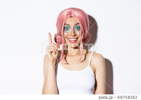 Close-up of woman in pink party wig and bright makeup, have idea, raising index finger in eureka sign, standing over white background 69758562