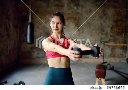 Girl lifting dumbbells in gym during workout. Young woman doing fitness. Healthy lifestyle 69758666