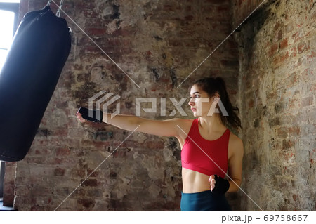 Young woman hits punching bag during a boxing training. Female boxer doing fitness. Young woman hits punching bag during a boxing training. Female boxer doing fitness. 69758667