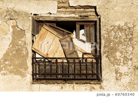 Front view of and aged and stained window with boards 69760340