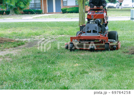 Close up of man using a lawn mower a gardener cutting grass by lawn mower Close up of man using a lawn mower a gardener cutting grass by lawn mower 69764258