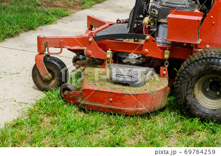 Gardening activity, lawn mower cutting the grass. Gardening activity, lawn mower cutting the grass. 69764259
