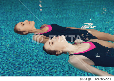 Girls in swimsuits lie on their backs and swim. Girls in swimsuits lie on their backs and swim. 69765224