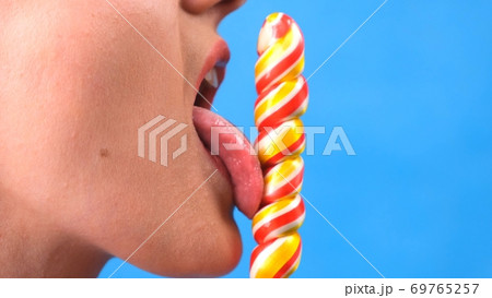 sexy brunette woman with lollipop isolated on a blue background. 69765257