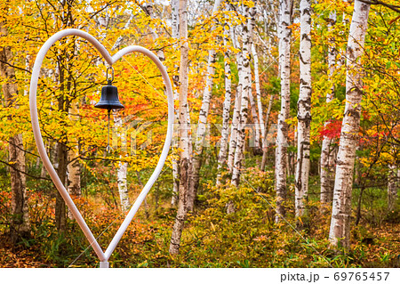 紅葉の中で愛を確かめるハートと鐘 69765457