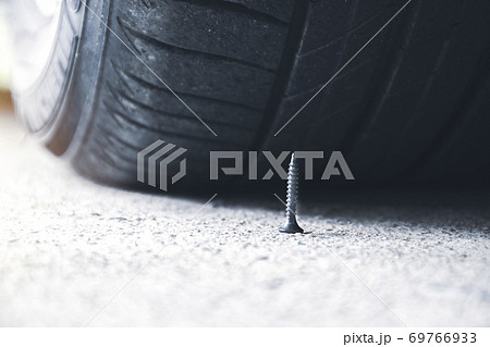 Sharp metal screw on road nearly to puncture a car tire Sharp metal screw on road nearly to puncture a car tire 69766933