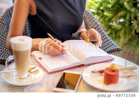 Business woman in black dress writes in notebook Business woman in black dress writes in notebook 69772330