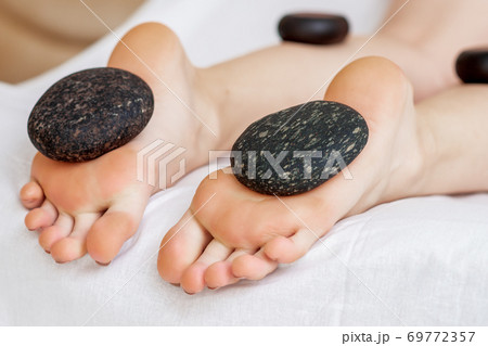 Hot stones lying on female feet Hot stones lying on female feet 69772357