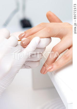 Manicure master applying beige nail polish 69772373