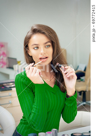 Woman applying gloss to the lips 69772415