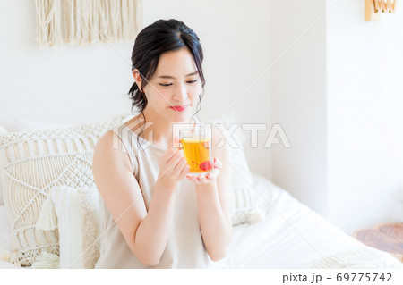 ベッドに座って微笑む女性 ベッドに座って微笑む女性 69775742