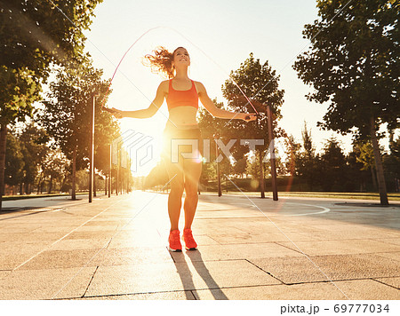 Athletic woman with jumping rope training in park. Athletic woman with jumping rope training in park. 69777034