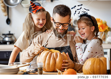 happy family father and children prepare for Halloween by carving pumpkins at home in kitchen. happy family father and children prepare for Halloween by carving pumpkins at home in kitchen. 69777036