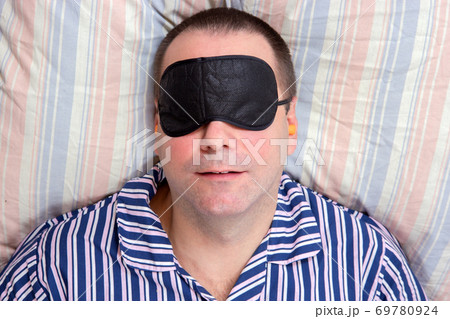 A man sleeping with a mask on eyes A man sleeping with a mask on eyes 69780924