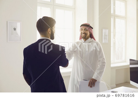 Handshake of arabic and european businesspeople in office. 69781616