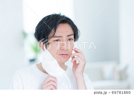 朝マスクをつけようとする笑顔の若い男性 69781860