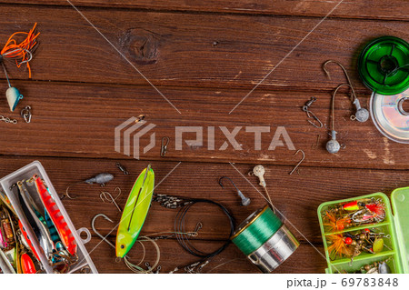 Different fishing tacles with lures and reels on wooden brown background with place for text. Different fishing tacles with lures and reels on wooden brown background with place for text. 69783848