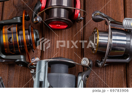 Different fishing tacles with lures and reels on wooden brown background with place for text. Different fishing tacles with lures and reels on wooden brown background with place for text. 69783906