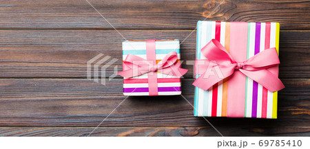 Beautiful gift box with a colored bow on the dark wooden table. Top view banner with copy space for you design Beautiful gift box with a colored bow on the dark wooden table. Top view banner with copy space for you design 69785410