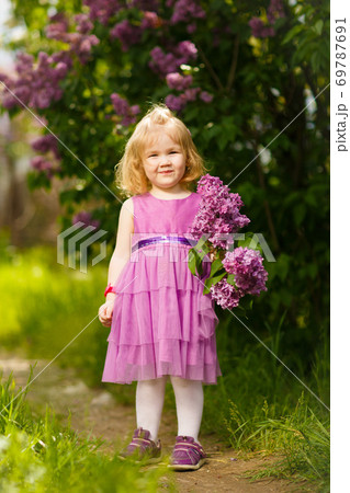 small girl near bush of lilac with a bouquet small girl near bush of lilac with a bouquet 69787691