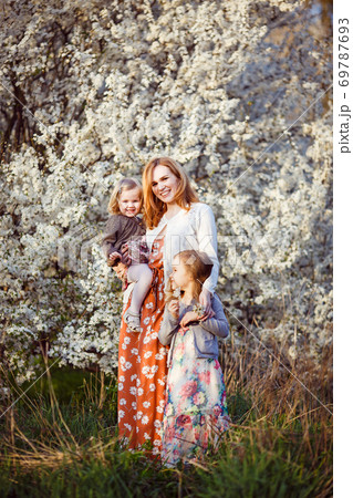 mom with two kids by bush with white flowers mom with two kids by bush with white flowers 69787693
