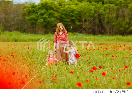 children with mom picking flowers in poppy field 69787964