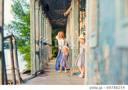 mom and kids standing on porch of old wooden house mom and kids standing on porch of old wooden house 69788254