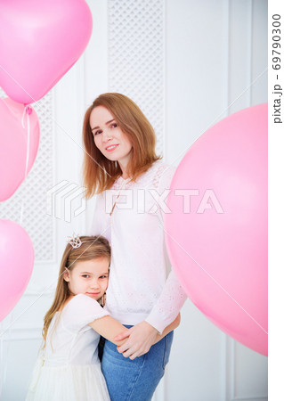mom and daughter on white wall with pink balloons. mom and daughter on white wall with pink balloons. 69790300