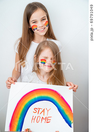 two funny girls drew rainbow and poster stay home. two funny girls drew rainbow and poster stay home. 69791049