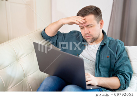 freelancer with head hurts working lying on couch 69792053
