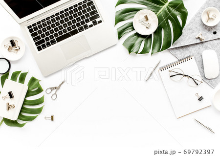 Home office workspace mockup with laptop, tropical leaves Monstera, clipboard, notebook and accessories on white background. Flat lay, top view Home office workspace mockup with laptop, tropical leaves Monstera, clipboard, notebook and accessories on white background. Flat lay, top view 69792397