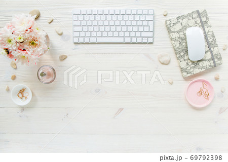 Top view office desk. Workspace with, computer, chrysanthemum, clipboard. Women's fashion accessories isolated on white wooden background. Flat lay Top view office desk. Workspace with, computer, chrysanthemum, clipboard. Women's fashion accessories isolated on white wooden background. Flat lay 69792398
