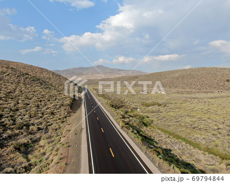 Aerial view of scenic road in the middle of green desert valley in Mono County 69794844