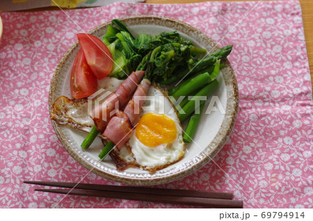 朝食アスパラベーコンと目玉焼きと野菜の写真素材