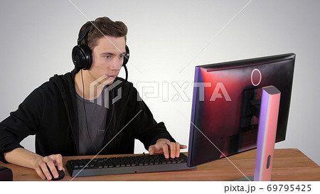 Concentrated angry brunette man playing video game on gradient b 69795425