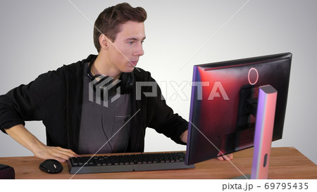 Nervous man watching video games on a PC computer on gradient ba 69795435