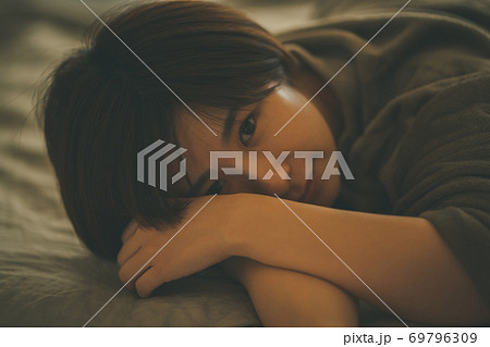 ベッドに寝そべるパジャマの女性 ベッドに寝そべるパジャマの女性 69796309