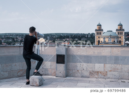 Young man on observation deck looking through telescope on old hungerian town Eger 69799486