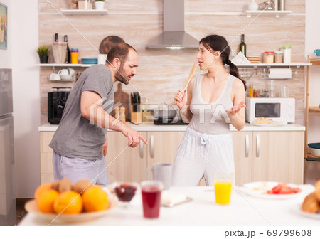 Cheerful couple dancing in kitchen Cheerful couple dancing in kitchen 69799608