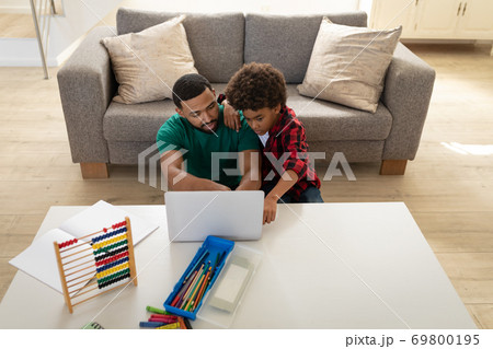 Father and son using laptop at home 69800195