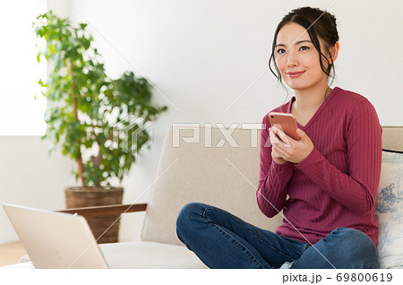 テレワーク中にソファーでスマホを操作する女性 テレワーク中にソファーでスマホを操作する女性 69800619