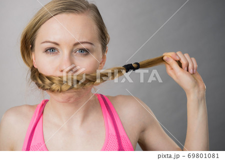 Woman covering her mouth with blonde braid 69801081