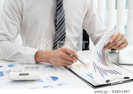 The hands of a male businessman are analyzing and calculating the annual income and expenses in a financial graph that shows results To summarize balances overall in office 69801497