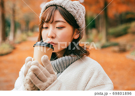 冬の公園でホットドリンクを飲む女性 69801896