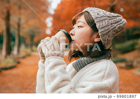 冬の公園でホットドリンクを飲む女性 69801897