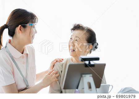 ビデオ通話をしているシニア女性とその介助スタッフ 69801979