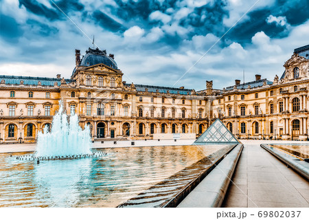 PARIS, FRANCE - JULY 03, 2016 :Glass pyramid and the Louvre museum. The Louvre is the biggest museum in word with nearly 35,000 historical artefact's. PARIS, FRANCE - JULY 03, 2016 :Glass pyramid and the Louvre museum. The Louvre is the biggest museum in word with nearly 35,000 historical artefact's. 69802037